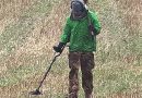 A man with a metal detector crosses a field in Devon