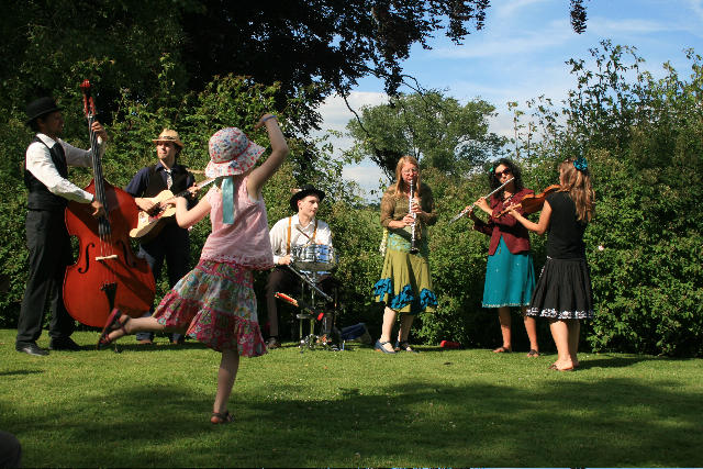 A young girl dances in a field as the band Hazaar! play